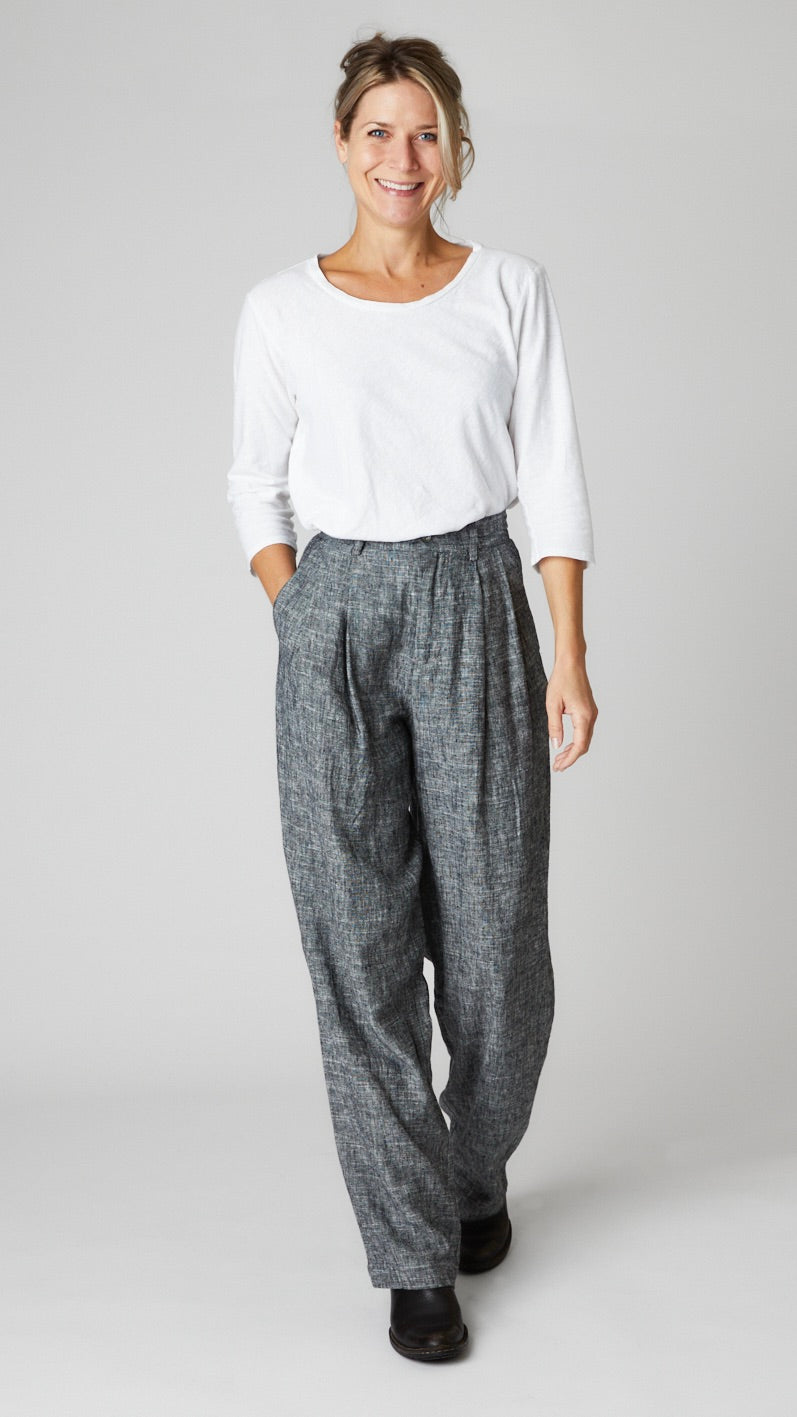 Model wearing white cotton-linen knit 3/4 sleeve bias cut tee, black chambray high-waisted linen trouser with pleats, and black leather boots.