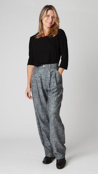 Model wearing black cotton-linen knit 3/4 sleeve bias cut tee, black chambray high-waisted linen trouser with pleats, and black leather boots.