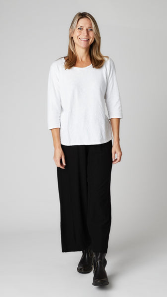 Model wearing white cotton-linen knit 3/4 sleeve bias cut tee, black cotton-linen knit cropped dart pant, and black leather boots.