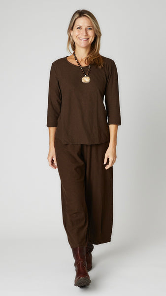 Model wearing mahogany cotton-linen knit 3/4 sleeve bias cut tee, chocolate cotton-linen knit cropped dart pant, and brown leather boots.