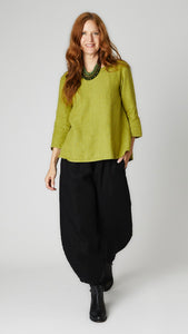 Model wearing fern linen A-line top with 3/4 sleeves, black linen lantern pants, and black leather boots. 