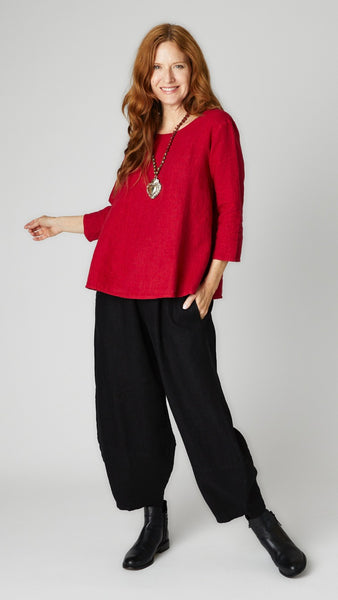 Model wearing cardinal linen A-line top with 3/4 sleeves, black linen lantern pants, and black leather boots. 