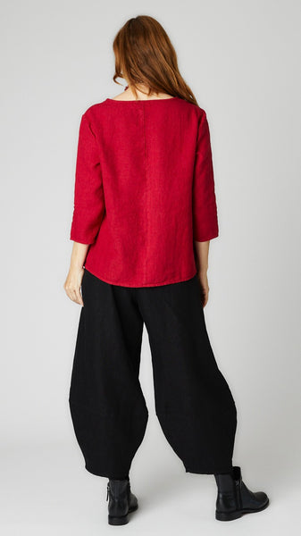 Model wearing cardinal linen A-line top with 3/4 sleeves, black linen lantern pants, and black leather boots. 