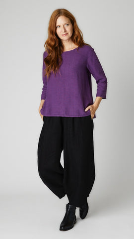 Model wearing mulberry linen A-line top with 3/4 sleeves, black linen lantern pants, and black leather boots. 