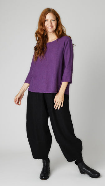 Model wearing mulberry linen A-line top with 3/4 sleeves, black linen lantern pants, and black leather boots. 