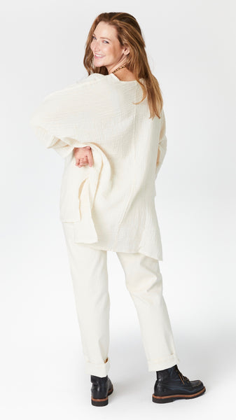 Model wearing natural/cream 3/4 sleeve, split hem, flowy high-low tunic in double cotton, with ecru straight leg jeans, and black lace-up leather boots.