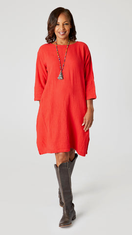 Model wearing cherry red crop-sleeve knee length cotton dress with side seam pockets, beaded necklace with jade pendant, and black leather boots.