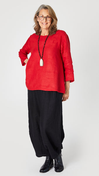 Model wearing red linen A-line top with 3/4 sleeves, black linen lantern pants, and black leather boots.