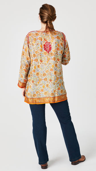 Rear view of model wearing red and amber embroidered silk tunic shows rear embroidered detail.