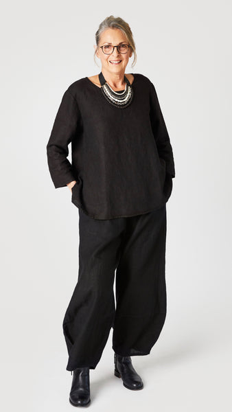 Model wearing black linen A-line top with 3/4 sleeves, black linen lantern pants, and black leather boots.