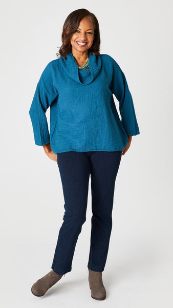 Model wearing teal double cotton cowl neck top with 3/4 sleeves, natural waist hemline and boxy fit, with indigo straight leg jeans, and suede boots.