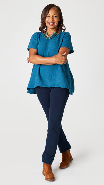  Model wearing teal short sleeve cotton top with scoop neck and flared waist, black cropped wideleg double cotton pant, Stephanie Leigh necklace, and brown ankle boots.