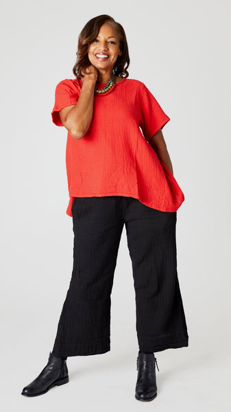  Model wearing cherry red short sleeve cotton top with scoop neck and flared waist, black cropped wideleg double cotton pant, Stephanie Leigh necklace, and black ankle boots.