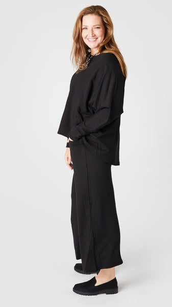 Model wearing black cropped palazzo pant, black long sleeve boatneck top, and black lug sole loafers.