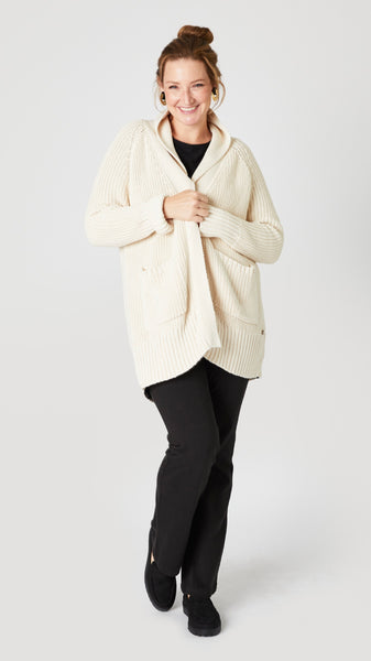 Model wearing cream cotton handknit oversized cardigan (without buttons) over black jersey tee, black straight leg jean, and black suede loafer. 