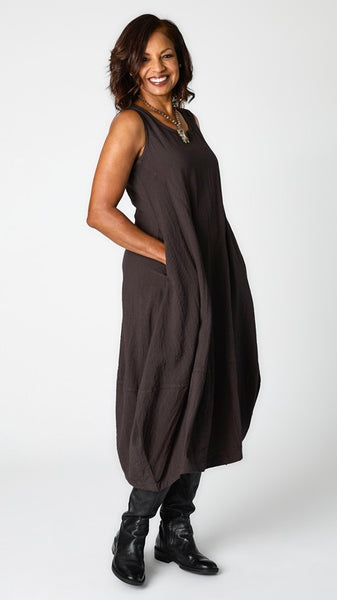 Model wearing "mineral" sleeveless rayon dress with tulip hemline and round neck, and black leather boots. 