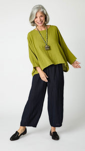 Model wearing cropped fig rayon top with high round neckline, dropped shoulders and ¾ sleeves, black cropped dart pants, and black loafers. 