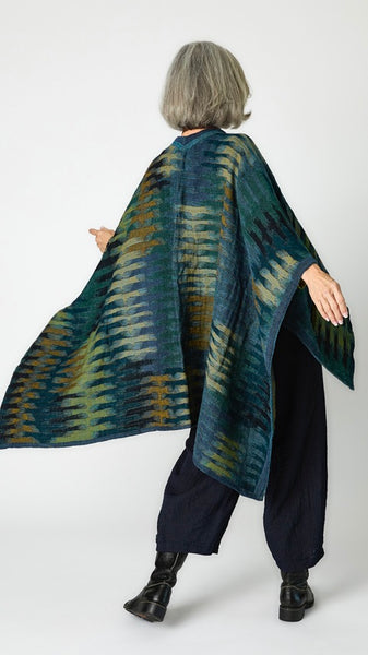 Rearview of model wearing moroccan green boiled wool cape. 