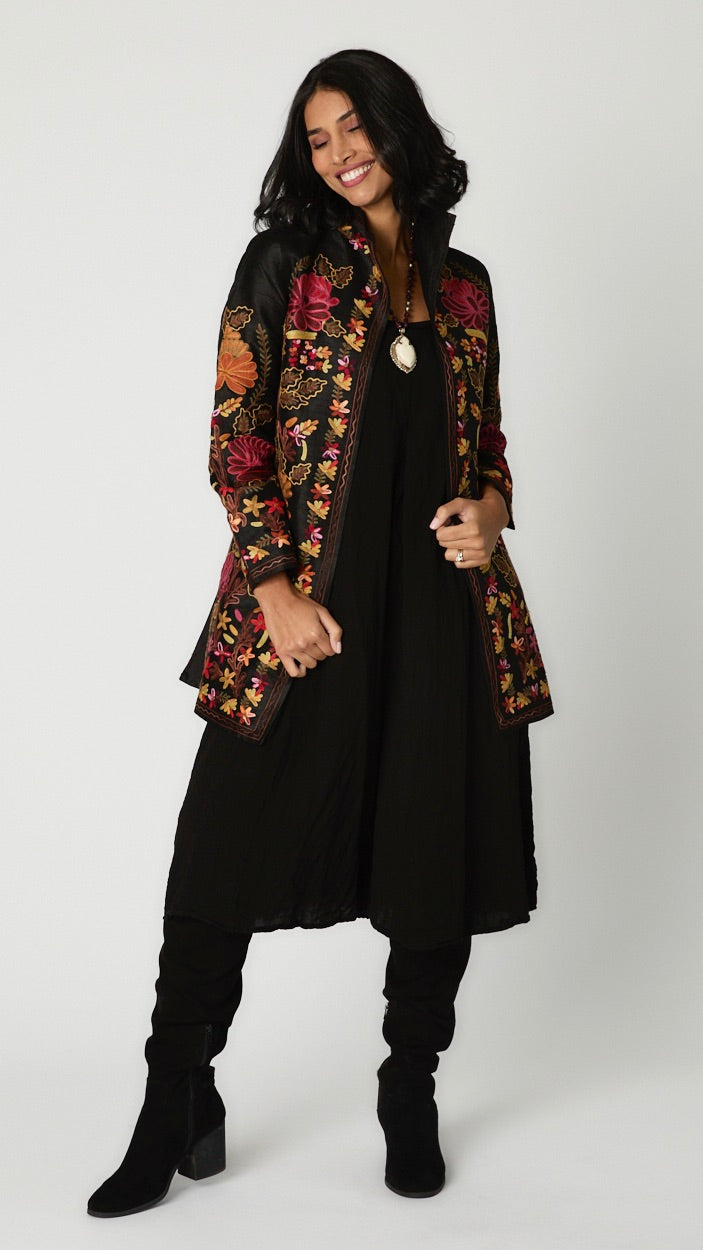 Model wearing silk duster with deep red, rust, and mustard embroidery over black rayon romper and black suede boots.