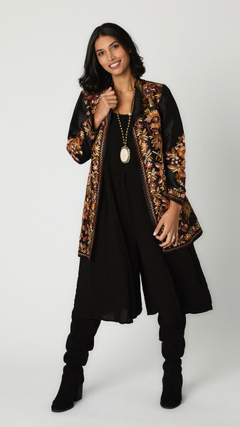 Model wearing black silk duster embroidered in brown tones over black rayon romper and black suede boots.