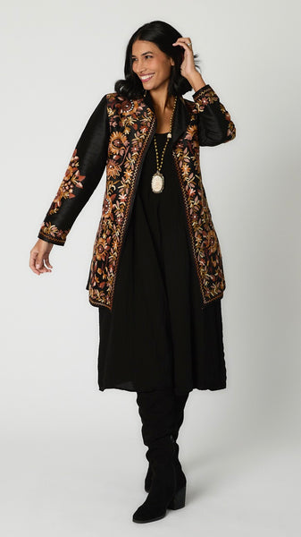 Model wearing black silk duster embroidered in brown tones over black rayon romper and black suede boots.