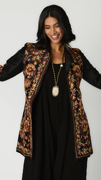 Model wearing bone Buddha necklace with brass beads, black rayon romper, and embroidered silk duster. 