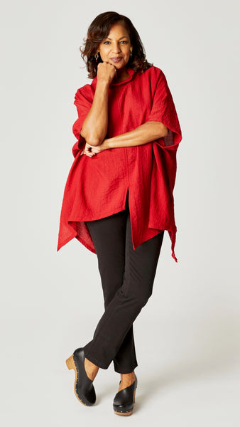 Model wearing red loose cowl neck tunic with asymmetrical hem and 3/4 sleeves, and black straight leg jeans.