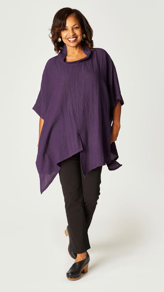 Model wearing eggplant loose cowl neck tunic with asymmetrical hem and 3/4 sleeves, and black straight leg jeans.