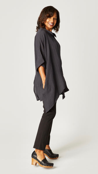 Model wearing black pearl loose cowl neck tunic with asymmetrical hem and 3/4 sleeves, and black straight leg jeans.
