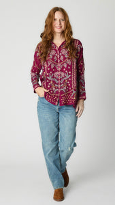 Model wearing floral embroidered "rose wine" button-up top with light wash straight leg jeans, and brown suede boots. 