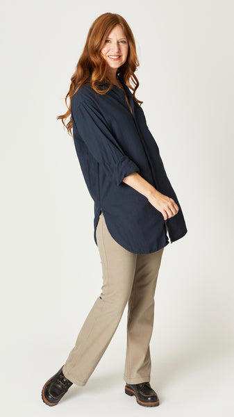 Model wearing ink relax fit button-up shirt with long sleeves, front pocket, and hi-lo hemline, with geode necklace, taupe bootcut jeans, and black boots.
