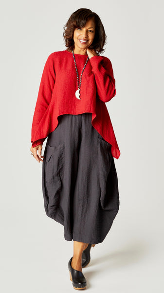 Model wearing red zinc long sleeve cropped top with A-line silhouette, black pearl double pocket pant, and bone moon pendant necklace.