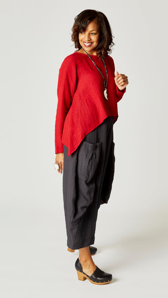 Model wearing red zinc long sleeve cropped top with A-line silhouette, black pearl double pocket pant, and bone moon pendant necklace.