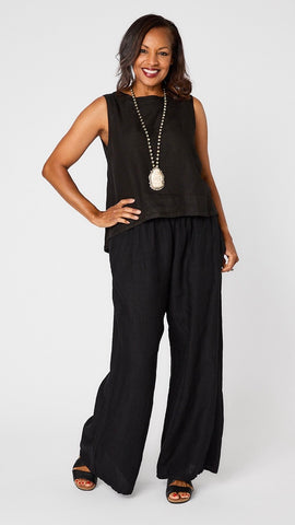 Model wearing black linen sleeveless tank with hi-lo silhouette, bone buddha pendant necklace, black wideleg linen pants, and black sandals.