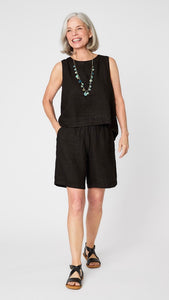 Model wearing black linen sleeveless tank with hi-lo silhouette, turquoise charm necklace, black linen knee length shorts, and black leather sandals.