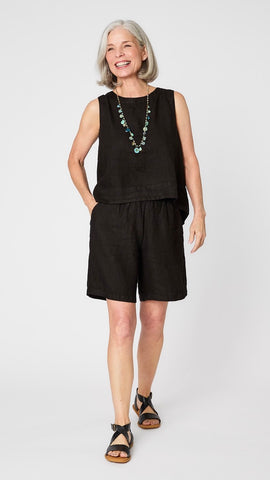 Model wearing black linen sleeveless tank with hi-lo silhouette, turquoise charm necklace, black linen knee length shorts, and black leather sandals.