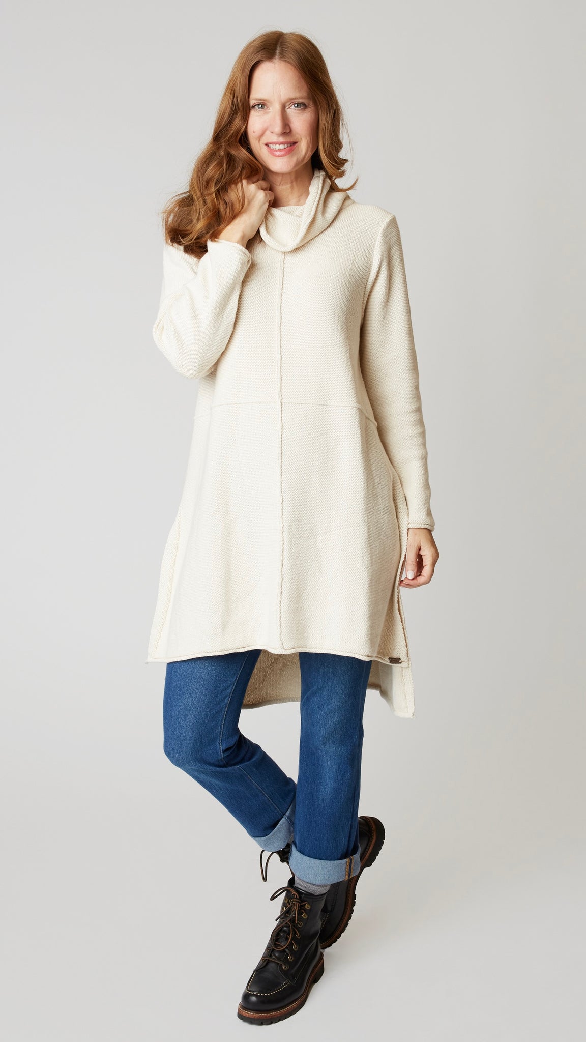 Model wearing cotton tunic-length sweater with high-low hemline, midwash boyfriend jeans, and black leather boots.