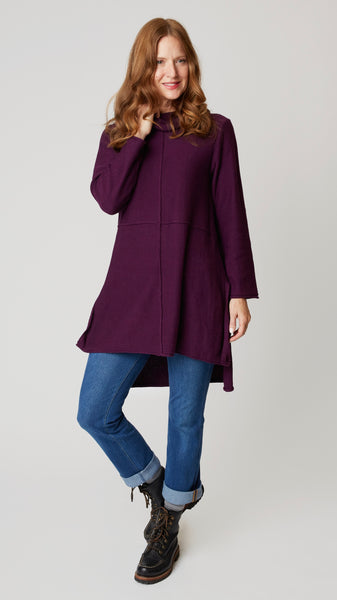 Model wearing cotton tunic-length sweater with high-low hemline, midwash boyfriend jeans, and black leather boots.