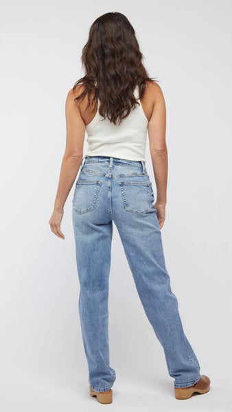 Model wearing white tank top, straight-leg, high-waisted mid-wash jean, and light brown clogs. 