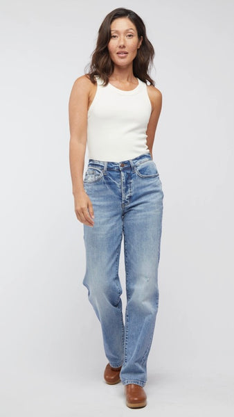 Model wearing white tank top, straight-leg, high-waisted mid-wash jean, and light brown clogs. 