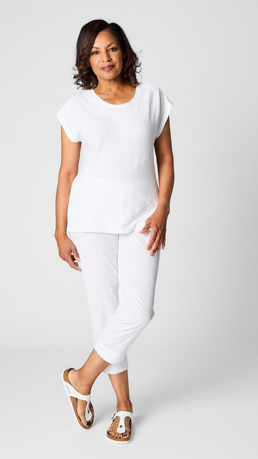 Model posing in white cropped sleeve box top, white tapered cropped pants in organic poplin, and white sandals. 