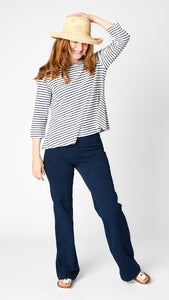 Model wearing blue and white striped boatneck shirt with 3/4 sleeves, indigo bootcut jeans and white sandals. 