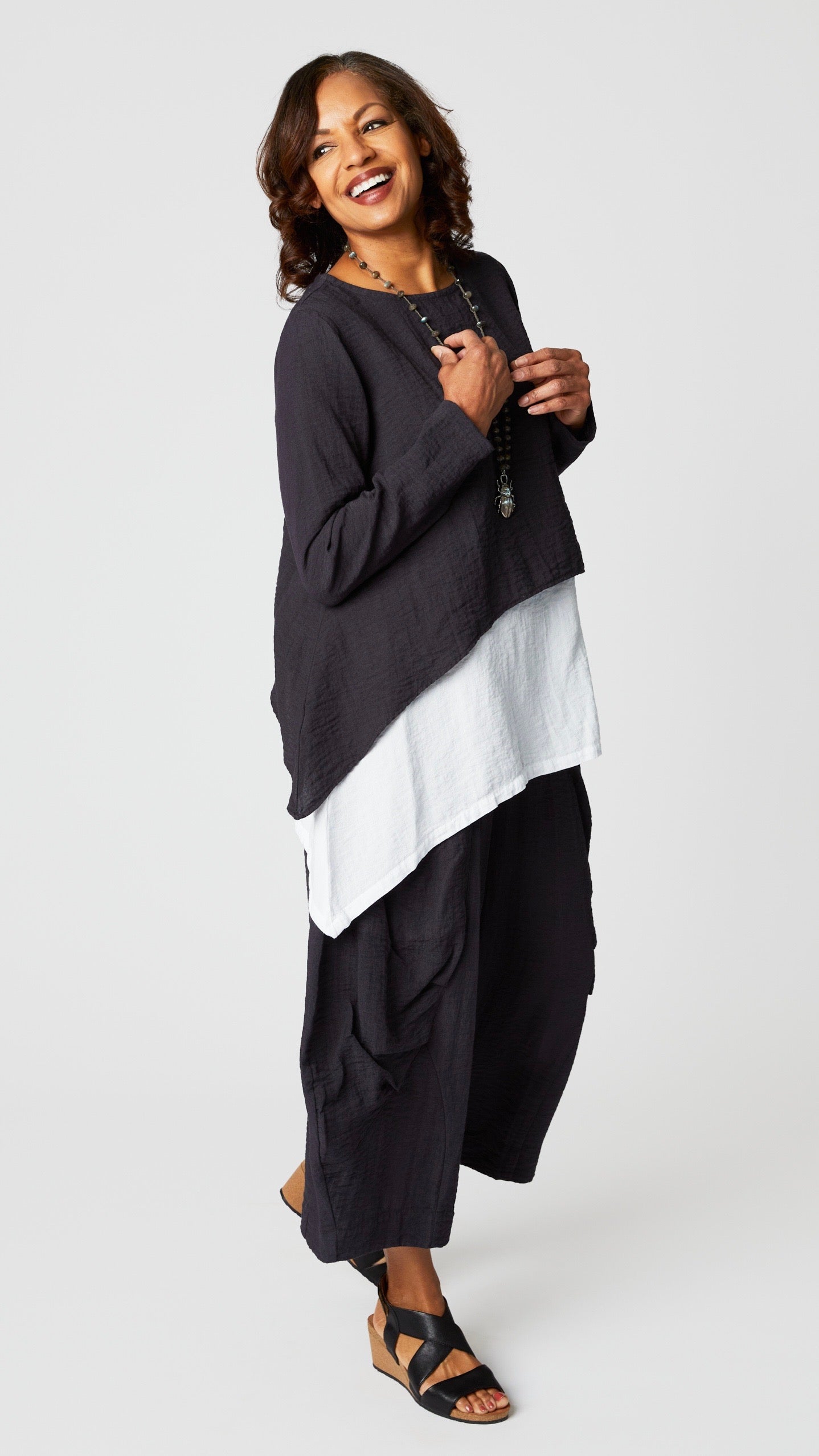 Model wearing black pearl long sleeve cropped top with A-line silhouette, chalk long tank, black pearl double pocket pant, and beetle pendant necklace.