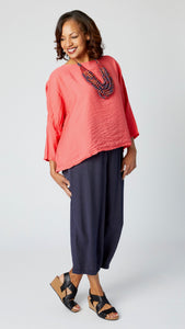 Model wearing navy rayon cropped dart pant, coral red cropped rayon top with dropped shoulder and 3/4 sleeves, and black sandals.