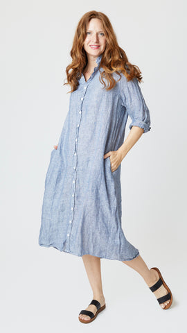 Model wearing chambray linen button-up, duster length, shirtdress with collar and black leather sandals.