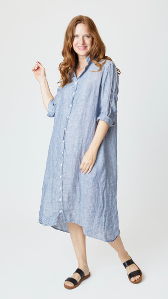 Model wearing chambray linen button-up, duster length, shirtdress with collar and black leather sandals.