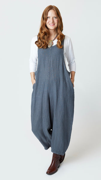 Model wearing gray linen overalls with cropped dart legs, white 3/4 sleeve top, and brown leather boots.