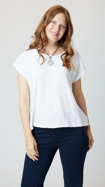 Model wearing white cotton-linen jersey top with cropped sleeves, boatneck, and boxy silhouette with indigo bootcut jeans.