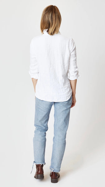 Model wearing white double cotton button-up shirt with light-wash jeans, and brown leather boots.