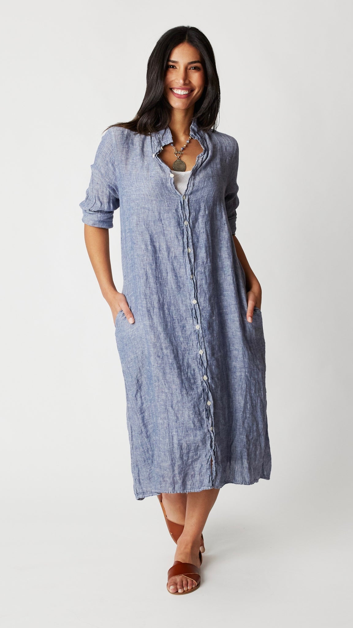 Model wearing chambray linen button-up, duster length, shirtdress with collar and brown leather sandals.